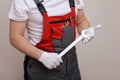 Repairman wearing a red and gray an overall, holding a wrench in his hand, standing on a white background. Maintenance service. Royalty Free Stock Photo