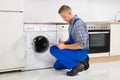 Repairman Writing On Clipboard In Kitchen Royalty Free Stock Photo