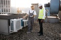 Repairmen standing and looking at conditioner on rooftop Royalty Free Stock Photo