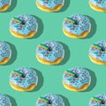 A repeating pattern of blue donuts with a rainbow on a green background. Flat lay Royalty Free Stock Photo