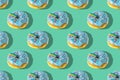 A repeating pattern of blue donuts with a rainbow on a green background. Flat lay Royalty Free Stock Photo