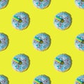 A repeating pattern of blue donuts with a rainbow on a yellow background. Flat lay Royalty Free Stock Photo