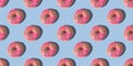 Repeating pattern of pink donuts on a blue background. Flat lay Royalty Free Stock Photo
