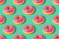 Repeating pattern of pink donuts on a green background. Flat lay Royalty Free Stock Photo