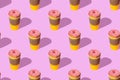 A repeating pattern of a red donut and a yellow cup of coffee on a pink background