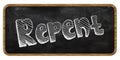 REPENT written in chalk on blackboard. Wood frame.