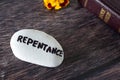 Repentance handwritten word on stone with closed holy bible book and flower on wooden background