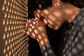 Repentant woman during confession near wooden partition in booth