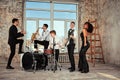 Repetition of multi ethnic jazz band in loft. Bass guitar player, electric guitar player, saxophonist and drummer at