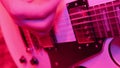 Repetition of rock music band. Cropped image of electric guitar player in a red light