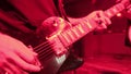 Repetition of rock music band. Cropped image of electric guitar player in a red light