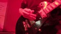 Repetition of rock music band. Cropped image of electric guitar player in a red light