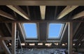 Replacing and installing 2 plastic skylight windows in mansard garret,or attic,of old house.Wooden load-bearing beams