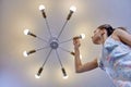 Replacing light bulb in LED lamp by woman indoors.