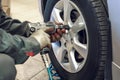 Replacing summer tires for winter using pneumatic wrench tool by mechanic worker after balancing wheels in car service garage shop Royalty Free Stock Photo