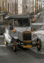 Replica of an old gray electric tourist car going up the slope of a cobblestone street with tram tracks through the old Alfama Royalty Free Stock Photo
