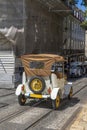 Replica of an old white electric tourist car going down a slope of a cobbled street with tram tracks through the old Alfama Royalty Free Stock Photo