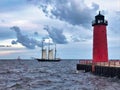 A replica sailing ship passes between two lighthouses on Lake Michigan.