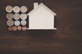 A replica wooden house and a pile of coins are placed on the old wooden floor.