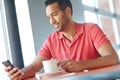 Replying to a friendly text message. A young man reading a text message while enjoying a cup of coffee. Royalty Free Stock Photo