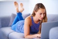 Replying to some emails. a young woman using her laptop on the sofa at home. Royalty Free Stock Photo