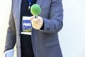 Journalist at news event, press conference or media interview holding green microphone. Broadcast journalism concept.