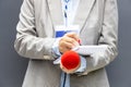 Reporter at press conference or media event, writing notes, holding microphone. Broadcast journalism concept.