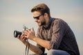 Reporter taking photo. Guy outdoors blue sky background. Vintage equipment. Blogger shooting vlog. Handsome blogger guy