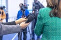 Journalists at news conference holding microphones making media interview with female politician or business woman Royalty Free Stock Photo