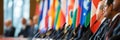 Diplomats engaging in discussions at an international conference with diverse country flags displayed prominently in the Royalty Free Stock Photo