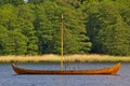 Reproduction of a wooden viking longship anchoring in a sheltered bay