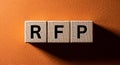 Request for proposal concept shown with rfp letters on wooden blocks against an orange textured background Royalty Free Stock Photo