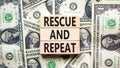 Rescue and repeat symbol. Concept words Rescue and repeat on wooden block on a beautiful background from dollar bills. Dollar Royalty Free Stock Photo