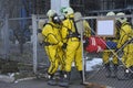 Rescuers in protective rubber suits and masks carrying the sufferer on stratcher from contaminated plant territory