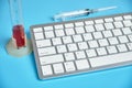 Research analyzes on a computer. Keyboard, test tube, syringe on a blue background