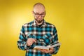 Research and business. A bald man with a beard and glasses, holding a book in his hands and carefully studying it through a