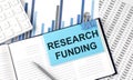 RESEARCH FUNDING on sticky note on notebook on the chart background Royalty Free Stock Photo