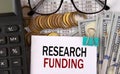 RESEARCH FUNDING - words on a white piece of paper on the background of a calculator, pennies and glasses Royalty Free Stock Photo