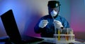 Research of a new dangerous strain of the virus. A bio scientist in protective lab clothing holds a test tube containing