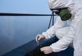 Worker scientist wearing protective coverall and gas mask doing ecological tests on the roof