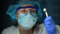 Researcher examining tablet, holding it in forceps, medication development