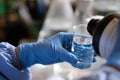 A researcher pouring a chemical into beaker glass