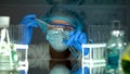 Researcher pouring green substance in blue liquid, checking water sediments