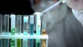 Researcher pouring liquid to sample boiling in test tube with warning symbol