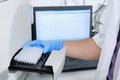 A researcher putting PCR plate on the thermal cycler for DNA amplification. Curve chart on monitor behind