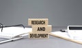 RESEARSH AND DEVELOPMENT text on wooden block with notebook,chart and calculator, grey background Royalty Free Stock Photo
