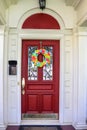 Resentails red front door with leaded glass in white house colorful Day of the Dead Halloween wreath