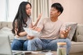 A resentful, angry Asian wife and husband are arguing about family household invoices on sofa Royalty Free Stock Photo