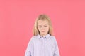 Resentful little girl in shirt on pink background