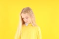 Resentful little girl in sweater on yellow background